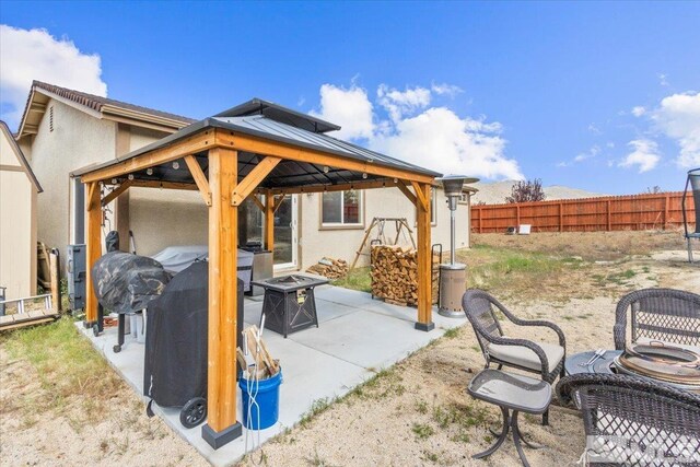view of patio featuring a fenced backyard, a gazebo, and an outdoor fire pit