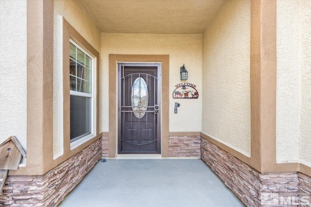 view of exterior entry featuring stucco siding and stone siding