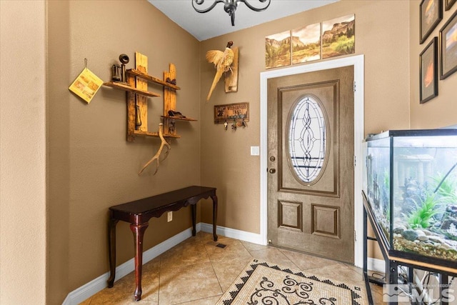 entryway featuring light tile patterned floors, baseboards, and a chandelier
