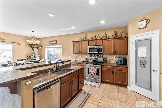 kitchen with brown cabinets, stainless steel appliances, a sink, and backsplash