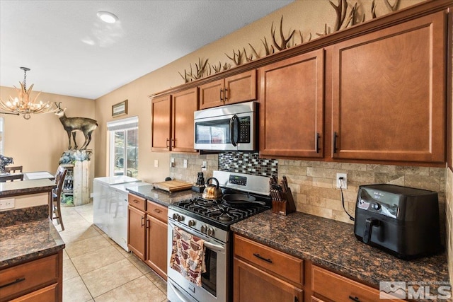 kitchen with brown cabinetry, decorative backsplash, a chandelier, and stainless steel appliances