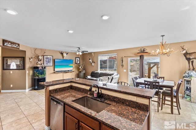 kitchen with stainless steel dishwasher, light tile patterned floors, hanging light fixtures, and a sink
