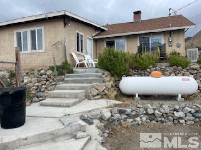 back of property featuring stucco siding and a chimney