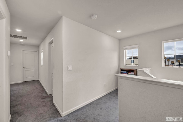 corridor featuring carpet floors, baseboards, and visible vents