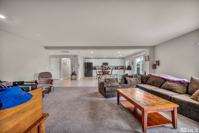 living area with recessed lighting, a textured ceiling, light colored carpet, and light tile patterned flooring