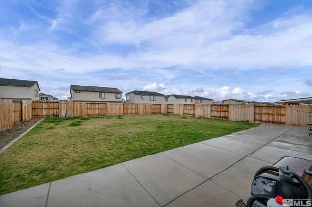 view of yard with a patio, a fenced backyard, and a residential view