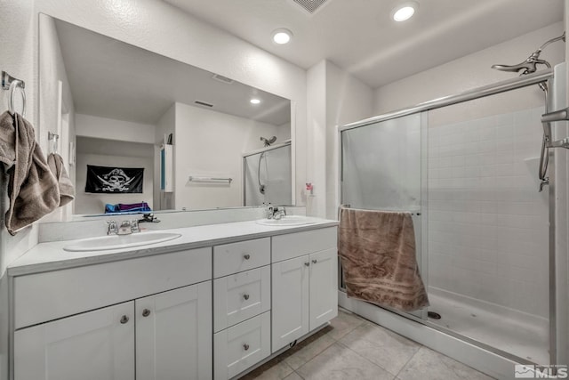 bathroom with double vanity, a shower stall, a sink, and tile patterned flooring