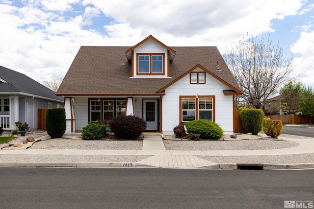 view of front of property with a shingled roof and fence