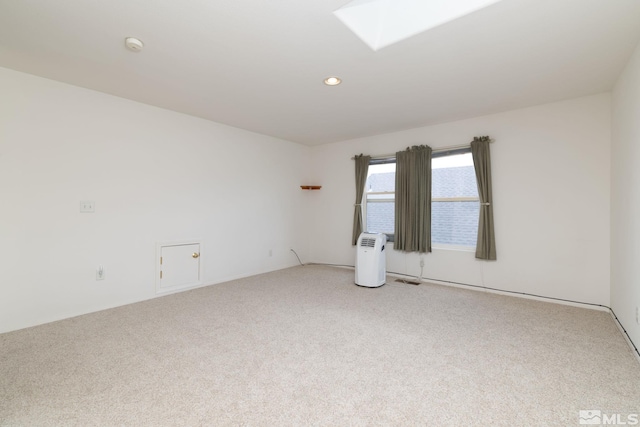 spare room featuring light colored carpet, a skylight, and recessed lighting