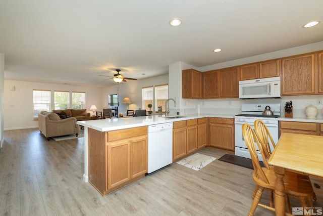 kitchen featuring white appliances, ceiling fan, a sink, a peninsula, and light countertops