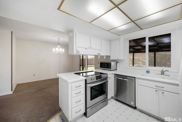 kitchen featuring stainless steel appliances, a sink, a peninsula, white cabinets, and light countertops