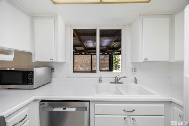 kitchen with appliances with stainless steel finishes, a sink, white cabinetry, and light countertops