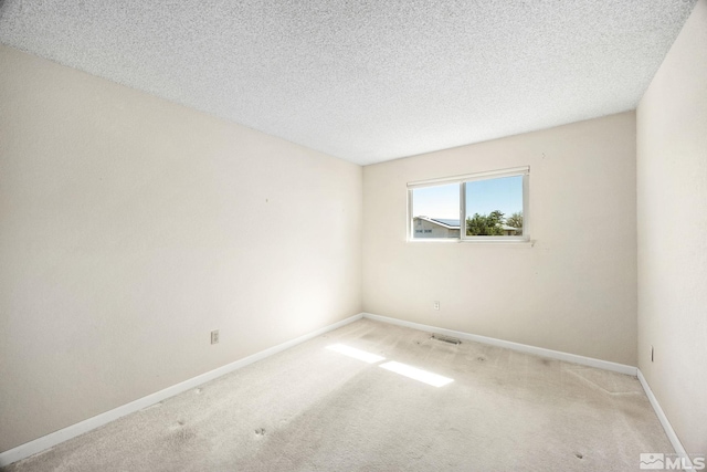 spare room with carpet, baseboards, and a textured ceiling
