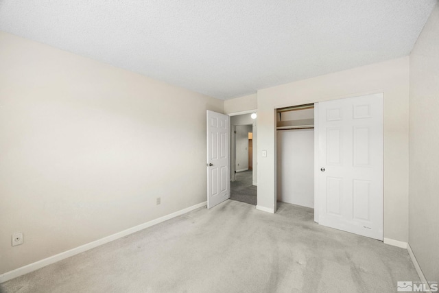 unfurnished bedroom with light carpet, baseboards, a closet, and a textured ceiling