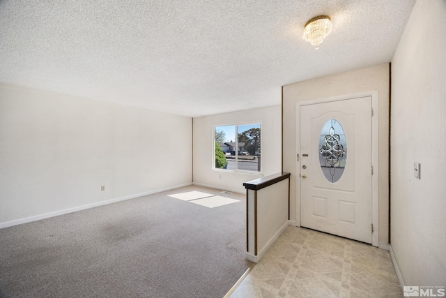 foyer with a textured ceiling, baseboards, and light colored carpet