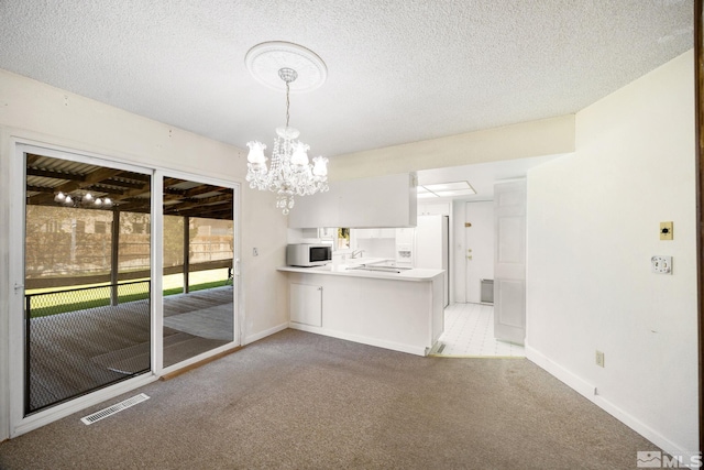 unfurnished dining area with light colored carpet, baseboards, a chandelier, a sink, and a textured ceiling