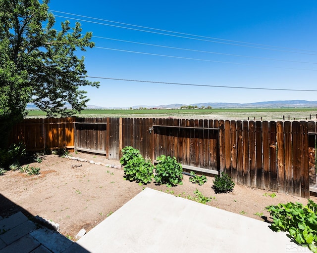 view of yard featuring fence, a patio area, and a mountain view