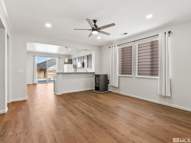 unfurnished living room featuring ceiling fan, wood finished floors, baseboards, recessed lighting, and ornamental molding