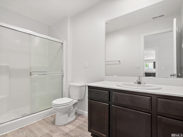 ensuite bathroom featuring toilet, wood finished floors, a shower stall, and vanity