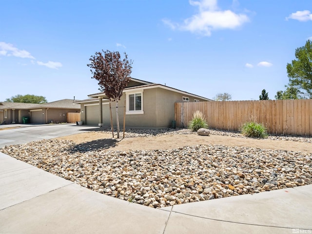 view of front of home with fence, concrete driveway, an attached garage, and stucco siding