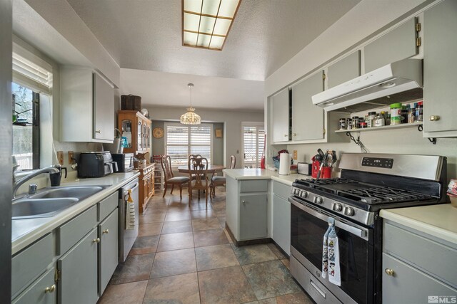 kitchen with appliances with stainless steel finishes, under cabinet range hood, a sink, light countertops, and healthy amount of natural light