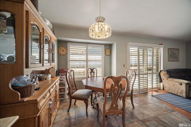 dining space featuring dark stone finish floors and a chandelier