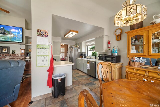 kitchen featuring appliances with stainless steel finishes, light countertops, a sink, and open floor plan