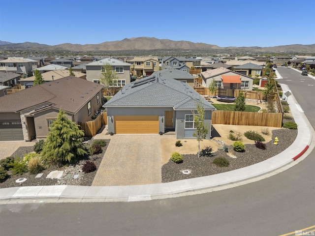 view of front of home featuring a residential view, a mountain view, fence, driveway, and a garage