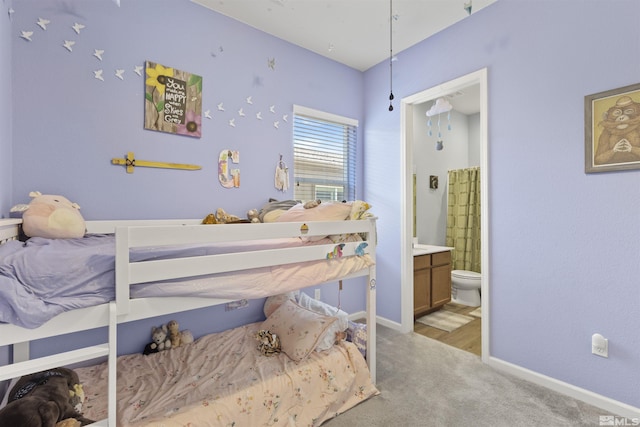 bedroom with light colored carpet, baseboards, and connected bathroom