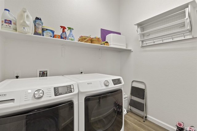 laundry area with washing machine and clothes dryer, baseboards, and light wood-style flooring