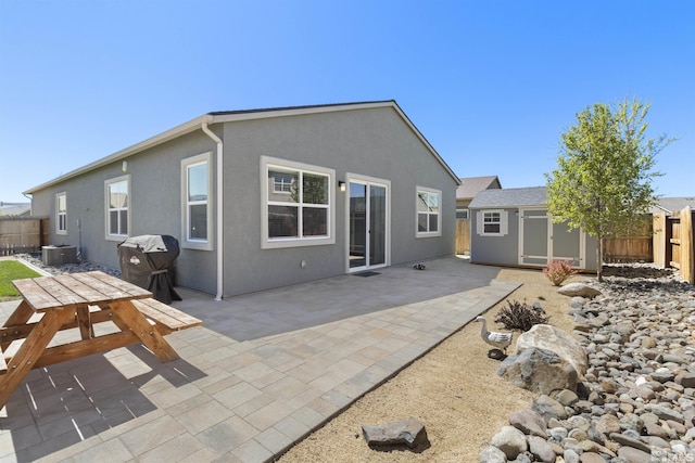 back of property with an outbuilding, a fenced backyard, a patio area, and a storage shed