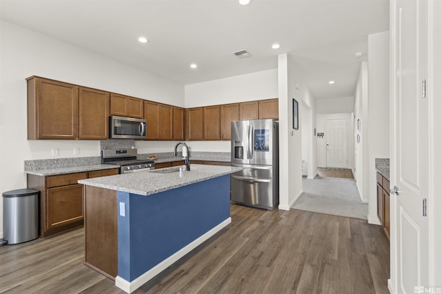 kitchen with appliances with stainless steel finishes, a sink, dark wood-style floors, a kitchen island with sink, and recessed lighting