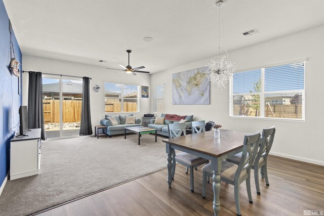 dining area with wood finished floors, ceiling fan, baseboards, and a chandelier