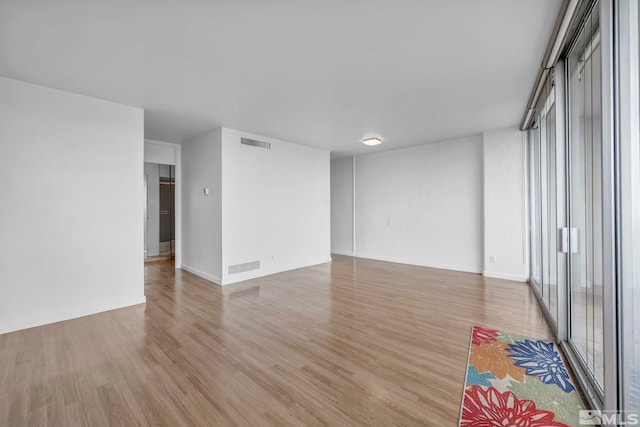 unfurnished room with light wood-style floors, baseboards, and plenty of natural light