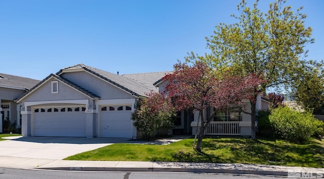 view of front facade with an attached garage, driveway, a front yard, stucco siding, and a tiled roof