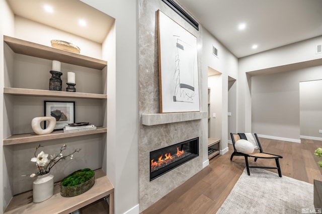 sitting room featuring wood finished floors, a tiled fireplace, baseboards, and recessed lighting