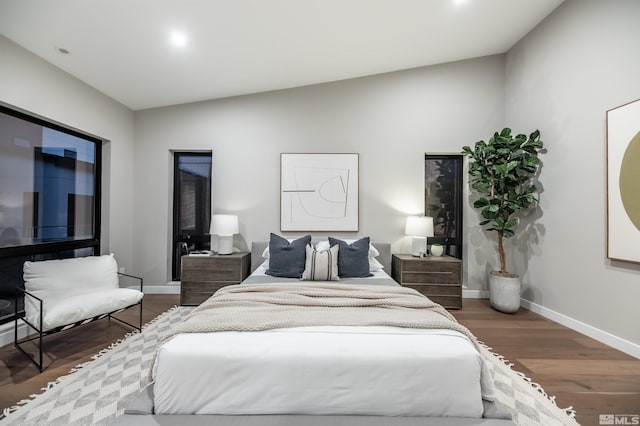 bedroom with baseboards, wood finished floors, and lofted ceiling