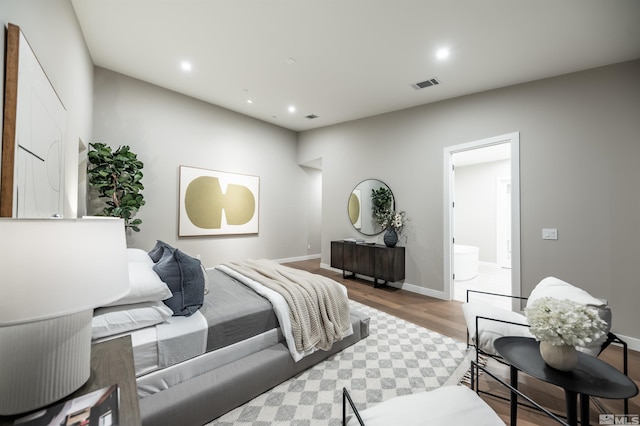 bedroom with wood finished floors, recessed lighting, baseboards, and connected bathroom
