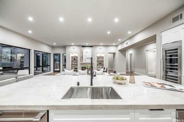 kitchen with a sink, open floor plan, wine cooler, light stone counters, and recessed lighting