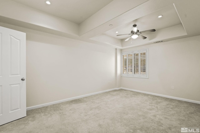 carpeted spare room with a raised ceiling, ceiling fan, recessed lighting, and baseboards