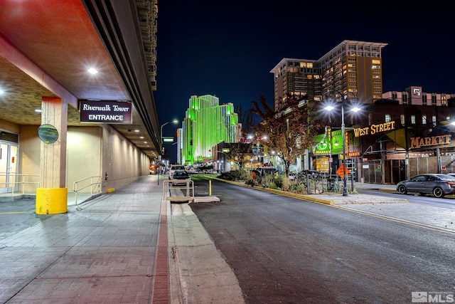 view of asphalt road featuring street lighting, curbs, and sidewalks