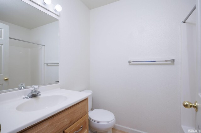 bathroom with toilet, vanity, and a shower