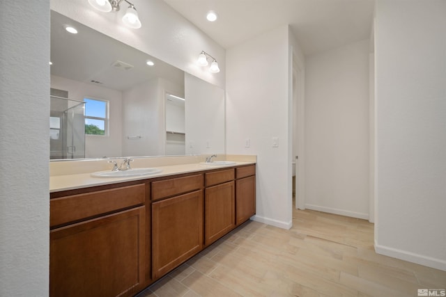 bathroom with a shower stall, double vanity, wood finished floors, baseboards, and recessed lighting