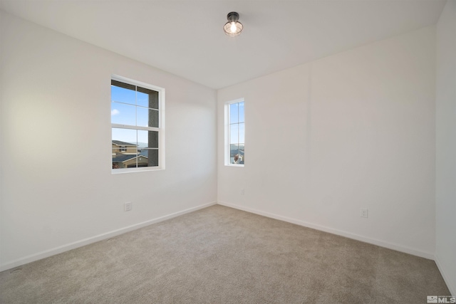 carpeted spare room featuring baseboards