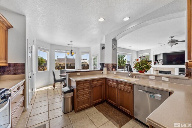 kitchen with a sink, stainless steel appliances, light countertops, brown cabinetry, and arched walkways