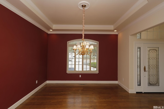 unfurnished dining area with a chandelier, dark wood finished floors, crown molding, baseboards, and a tray ceiling