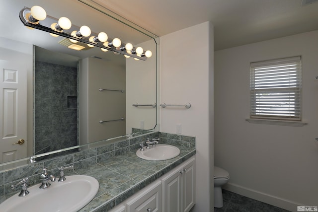 bathroom with toilet, double vanity, tile patterned flooring, and baseboards
