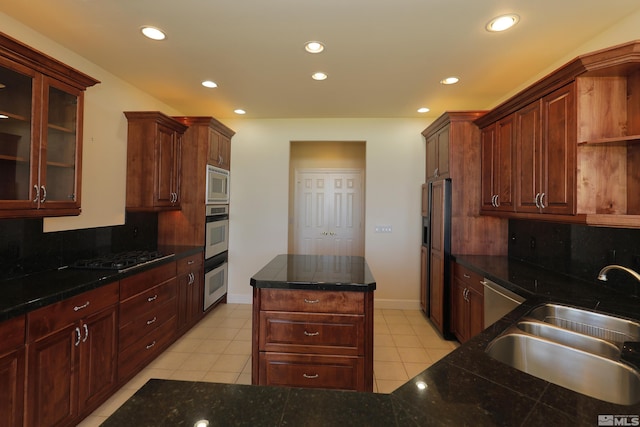 kitchen with a sink, built in appliances, recessed lighting, tasteful backsplash, and light tile patterned floors