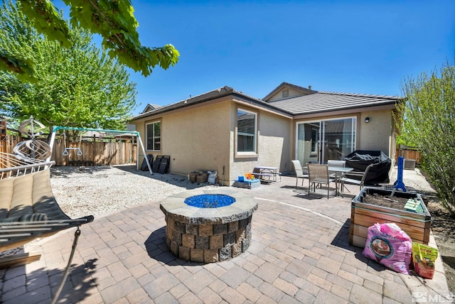 back of property featuring an outdoor fire pit, a fenced backyard, a patio area, and stucco siding