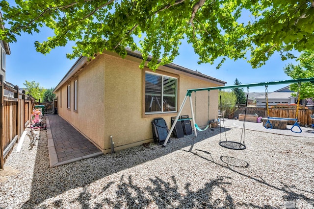 rear view of property with stucco siding, a patio, and a fenced backyard